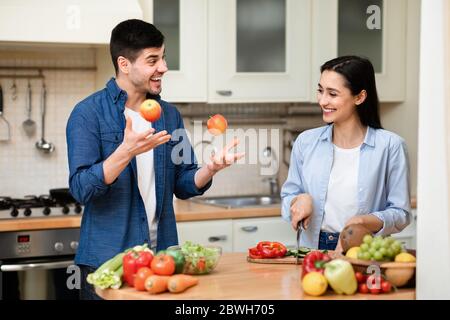 Schönes Paar, das das Abendessen mit Äpfeln jongliert Stockfoto