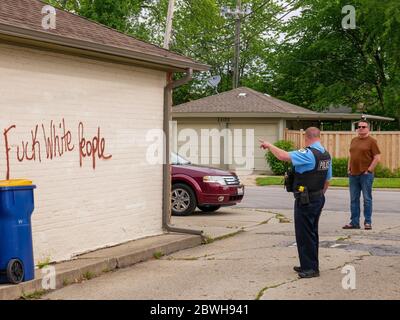 Oak Park Juni 2020. Ein Oak Park Police Evidence Technician untersucht rassistische Graffiti, die über Nacht in einigen Garagen auf der Nordseite dieses Chicagoer Vororts auftauchten. Offensichtlich wussten die Purpetratoren, wer auf jedem markierten Eigentum lebte, da sowohl Anti-Weiß- als auch Anti-Schwarz-Graffiti auf ausgewählten Eigenschaften verwendet wurden und mit dem Rennen der Hausbesitzer variierten. Stockfoto