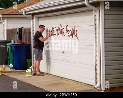 Oak Park Juni 2020. Ein Hausbesitzer reinigt rassistische Graffiti von seiner Garagentür. Die Graffiti erschien über Nacht auf der Nordseite dieses Chicagoer Vororts. Offensichtlich wussten die Purpetratoren, wer auf jedem getaggten Eigentum lebte, da sowohl anti-weiße als auch anti-schwarze Graffitti auf ausgewählten Eigenschaften verwendet wurde und mit dem Rennen der Hausbesitzer variierte. Stockfoto