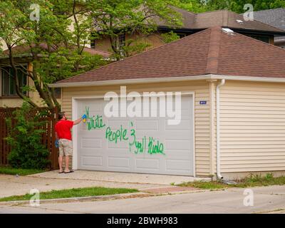 Oak Park Juni 2020. Ein Hausbesitzer reinigt rassistische Graffiti von seiner Garagentür. Das Graffiti erschien über Nacht auf der Nordseite dieses Chicagoer Vororts. Offensichtlich wussten die Purpetratoren, wer auf jedem getaggten Eigentum lebte, da sowohl anti-weiße als auch anti-schwarze Graffitii auf ausgewählten Eigenschaften verwendet wurde und mit dem Rennen der Hausbesitzer variierte. Stockfoto