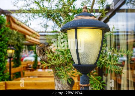 Gusseiserne Lampe in einem idyllischen Garten mit Holzbänken und Tischen Stockfoto