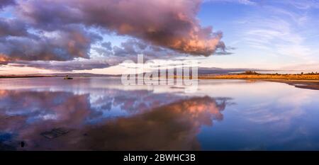 Blick auf den Sonnenuntergang auf die restaurierten Feuchtgebiete der South San Francisco Bay Area, mit dunklen Wolken, die sich auf der Wasseroberfläche und Diablo Mountain Range VISIB spiegeln Stockfoto