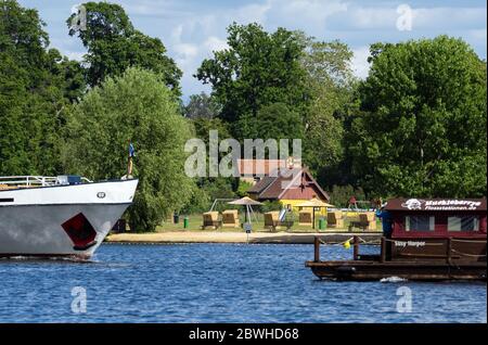 Potsdam, Deutschland. Mai 2020. Ein Ausflugsdampfer und ein Holzfloß passieren das lido im Park Babelsberg am Tiefsee. Nach Plänen der Stiftung Preußischer Kulturbesitz (SPSG) und der Stadt soll das lido bis 2022 in Richtung Humboldt-Brücke verlagert und verkleinert werden. Quelle: Soeren stache/dpa-Zentralbild/ZB/dpa/Alamy Live News Stockfoto
