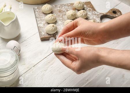 Frau bereitet leckere Knödel auf dem Tisch Stockfoto