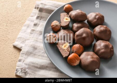 Teller mit leckeren Schokolade Bonbons und Haselnüssen auf dem Tisch Stockfoto