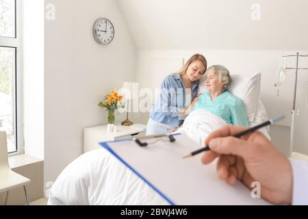 Junge Frau, die ihre Großmutter im Krankenhaus besucht Stockfoto