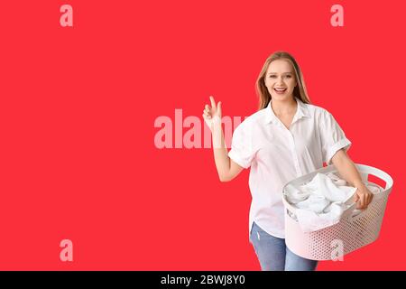 Junge Frau mit Wäsche, die etwas auf farbigem Hintergrund zeigt Stockfoto