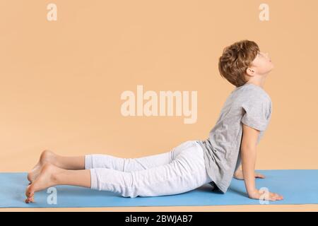 Niedlichen kleinen Jungen Yoga auf farbigen Hintergrund zu üben Stockfoto