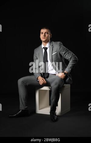 Schöner junger Mann in elegantem Anzug auf dunklem Hintergrund Stockfoto