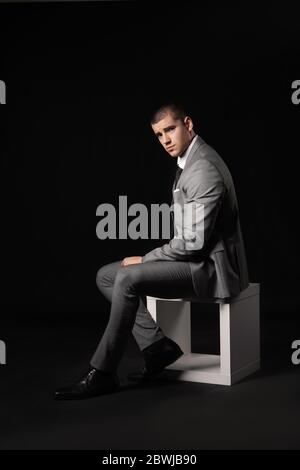 Schöner junger Mann in elegantem Anzug auf dunklem Hintergrund Stockfoto