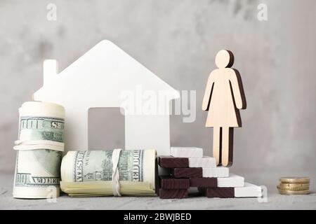 Figuren von Frau, Haus und Geld auf dem Tisch. Konzept der Schulden Stockfoto