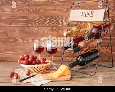 Halter mit Flaschen Wein und Käse auf Holzhintergrund Stockfoto