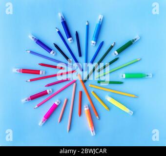 Zurück zur Schule Hintergrund mit verschiedenen Bleistiften, Marker und Wachsmalstifte in Regenbogenfarben auf pastellblauen Hintergrund. Flaches Lay-Design. Platz für Text. Stockfoto
