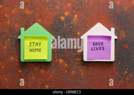 Modelle von Häusern mit Text ZU HAUSE BLEIBEN, LEBEN retten auf farbigen Hintergrund Stockfoto