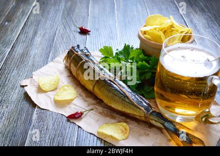 Biersnacks. Geräucherter Fisch, Pommes, ein Glas Bier auf einem Holztisch. Stockfoto