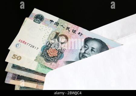 Yuan-Scheine in weißem Umschlag auf schwarzem Hintergrund. Chinesische Wirtschaft, Einkommen, Bonus oder Bestechung Konzept Stockfoto