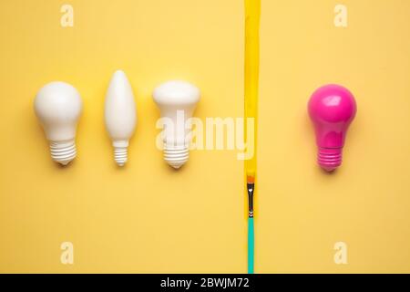 Rosa Glühbirne unter weißen auf farbigen Hintergrund. Konzept der Einzigartigkeit Stockfoto