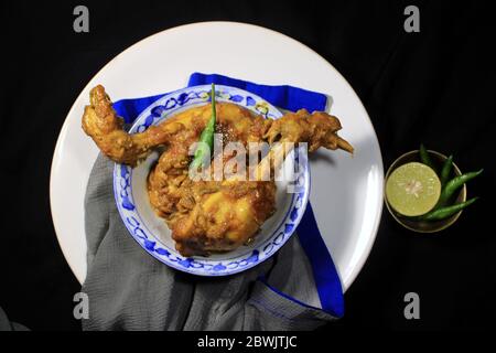 Gekochtes Hühnchen Curry in weißen Topf. Scharf und scharf Chicken Curry mit grüner Zitrone & Chili isoliert auf schwarzem Hintergrund. Stockfoto