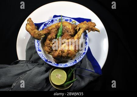 Gekochtes Hühnchen Curry in weißen Topf. Scharf und scharf Chicken Curry mit grüner Zitrone & Chili isoliert auf schwarzem Hintergrund. Stockfoto