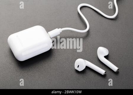 Moderne kabellose bluetooth-Kopfhörer mit Ladetasche auf dunkelschwarzem Hintergrund. Das Konzept der modernen Technologie, Gadgets. Stockfoto