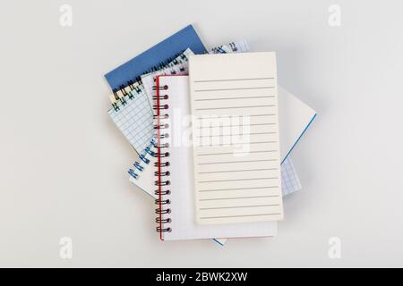 Ein Stapel von mehreren spiralförmigen Schulheften liegt auf einem weißen Tisch mit Bleistift, Bürokonzept Stockfoto