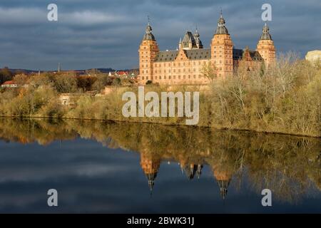 Schloss Johannisburg am Mainufer mit Spiegelung, strahlend in der Herbstabendsonne, berühmtes historisches Stadtschloss in Aschaffenburg, Stockfoto