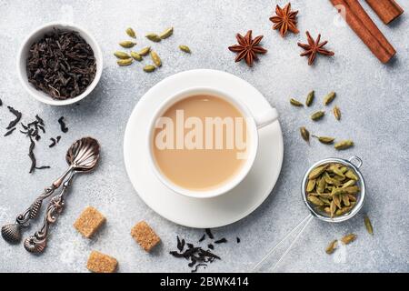 Indischer Tee mit Milch und Gewürzen. Kardamom Sticks Zimt Stern Anis Rohrzucker Stockfoto