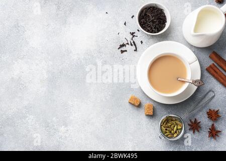 Indischer Tee mit Milch und Gewürzen. Kardamom Sticks Zimt Stern Anis Rohrzucker Beton grau Tabelle kopieren Raum. Stockfoto