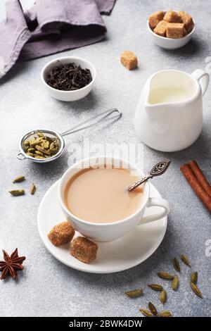 Indischer Tee mit Milch und Gewürzen. Kardamom Sticks Zimt Stern Anis Rohrzucker Stockfoto