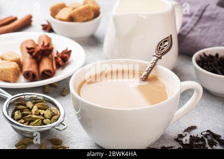 Indischer Tee mit Milch und Gewürzen. Kardamom Sticks Zimt Stern Anis Rohrzucker Stockfoto