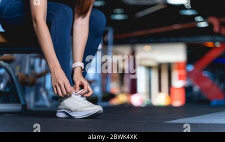 Junge asiatische Frauen binden Schnürsenkel vor dem Training und für die Sicherheit vorzubereiten, EINE gesunde Frau sitzt auf der Bank lehnend nach unten, um die Schnürsenkel zu binden Stockfoto