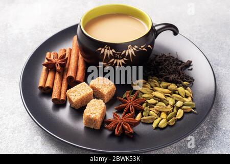 Indischer Tee mit Milch und Gewürzen. Kardamom Sticks Zimt Stern Anis Rohrzucker Stockfoto