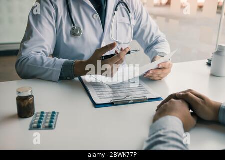 Arzt Hand halten Stift schreiben Patientenliste auf Notizblock und sprechen mit dem Patienten über Medikamente und Behandlung. Stockfoto