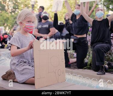 Bentonville, Arkansas, USA. Juni 2020. Ein Mädchen beobachtet, wie Protestierende Zeichen und Gesang während einer überwiegend friedlichen Demonstration über den Tod von George Gloyd auf dem Stadtplatz vor dem historischen Benton County Gerichtsgebäude aufschwingt. Als der Protest zu beenden schien, brach ein Konflikt mit Strafverfolgungsbehörden aus, die zwei Polizeifahrzeuge der Stadt und eine zweistündige Standzeit verursachten, bevor sie mit Tränengas zerstreut wurden. Quelle: Brent Soule/ZUMA Wire/Alamy Live News Stockfoto