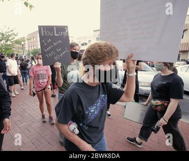 Bentonville, Arkansas, USA. Juni 2020. Ein älteres Paar kommt zusammen, während Protestierende Zeichen und Gesang während einer überwiegend friedlichen Demonstration über den Tod von George Gloyd auf dem Stadtplatz vor dem historischen Benton County Gerichtsgebäude aufschlagen. Als der Protest zu beenden schien, brach ein Konflikt mit Strafverfolgungsbehörden aus, die zwei Polizeifahrzeuge der Stadt und eine zweistündige Standzeit verursachten, bevor sie mit Tränengas zerstreut wurden. Quelle: Brent Soule/ZUMA Wire/Alamy Live News Stockfoto