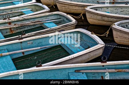Eine Reihe von alten blauen Booten dockten zusammen auf einem ruhigen See Stockfoto