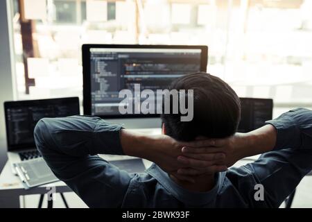 Asiatische Programmierer Mann sind entspannend und Blick auf den Code auf dem Computerbildschirm im Büro. Stockfoto