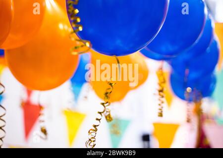 Bunte Luftballons, blau, Orangeund Dreiecksfahnen isoliert. Party und Geburtstag Konzept Stockfoto