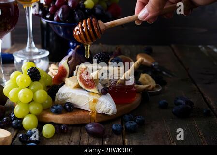 Rot- und Weißwein, Trauben, Käse und Honig über Holz- Tabelle. Stockfoto