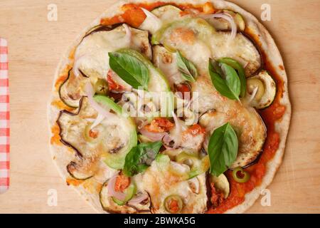 HAUSGEMACHTE AUBERGINEN, ZUCCINI, ZWIEBELPIZZA MIT CAPSICUM UND KÄSE MIT BASILIKUMBLÄTTERN Stockfoto