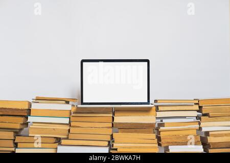 Laptop-Computer mit weißem Bildschirm auf dem Stapel alter Bücher. Alte versus neue Technologie und Bildung bedeutet Stockfoto