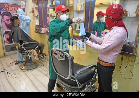 Beawar, Rajasthan, Indien - 1. Juni 2020: Ein Barbier, der persönliche Schutzausrüstung (PSA) trägt, gibt dem Kunden in seinem Salon am ersten Tag der COVID-19-Sperre 5.0 in Beawar eine Gesichtsmask. Kredit: Sumit Saraswat/Alamy Live News Stockfoto