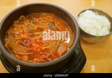 Kanne Kimchi jigae oder koreanischer Hot and Spicy Kimchi Eintopf serviert mit einer Schüssel Reis auf Holztisch Stockfoto