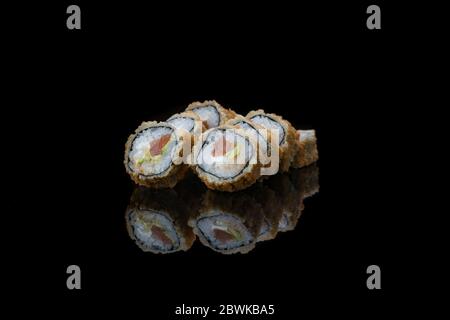 Eine Nahaufnahme von Lebensmitteln gebratene Sushi-Rollen isoliert auf schwarz. Reflexion Stockfoto