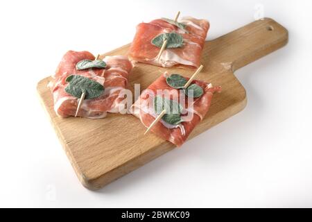 Vorbereitet Huhn saltimbocca mit luftgetrockneten Schinken und Salbeiblätter auf einem Küchenbrett auf einem weißen Hintergrund isoliert gewickelt, kopieren Raum, ausgewählten Fokus Stockfoto