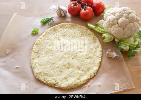 Rohe Pizza Basis aus geschreddertem Blumenkohl auf Backpapier, gesunde pflanzliche Alternative für Low Carb und ketogene Ernährung, Kopierraum, ausgewählten Fokus, n Stockfoto