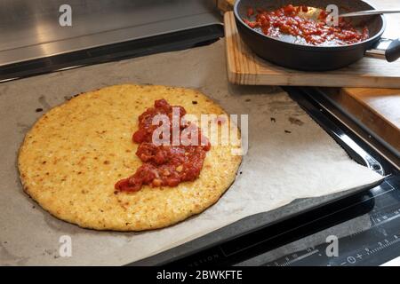 Gebackene Pizza Basis aus geschreddertem Blumenkohl und Käse halb mit Tomatensauce bedeckt, Kochen eine gesunde Alternative für die Abnehmen mit Low Carb oder Keto Stockfoto
