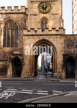 Bristol, England, Großbritannien - 25. Mai 2020: Ein Radfahrer fährt durch die gotische Torbogen-Kirche St. John an der Mauer, Teil der mittelalterlichen Stadtmauer von Brücke Stockfoto