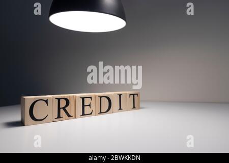 Das Wort Kredit aus Holzblöcken. Business- und Bankkonzept. Spotlicht auf weißem Hintergrund. Nahaufnahme. Stockfoto