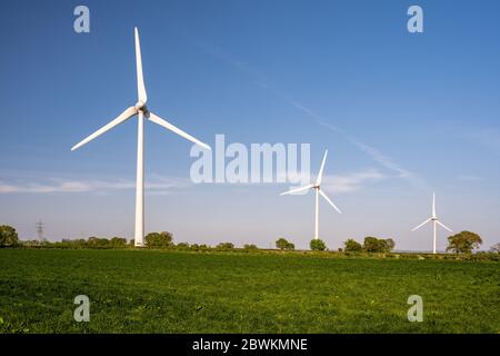 Windkraftanlagen stehen in Ackerland neben National Grid Hochspannungsleitungen in der Nähe von Alveston in South Gloucestershire. Stockfoto